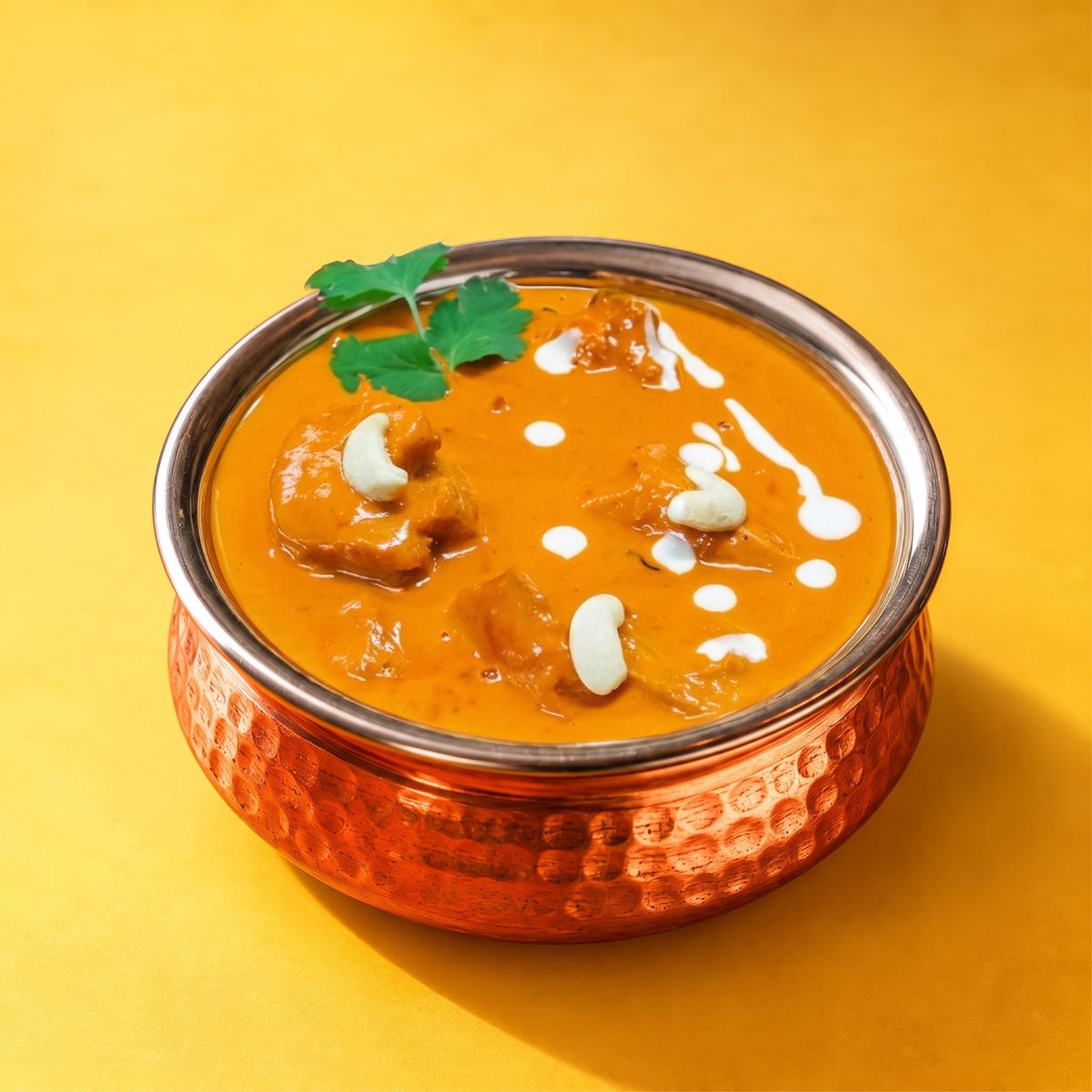 Butter chicken with a swirl of cream in a copper bowl
